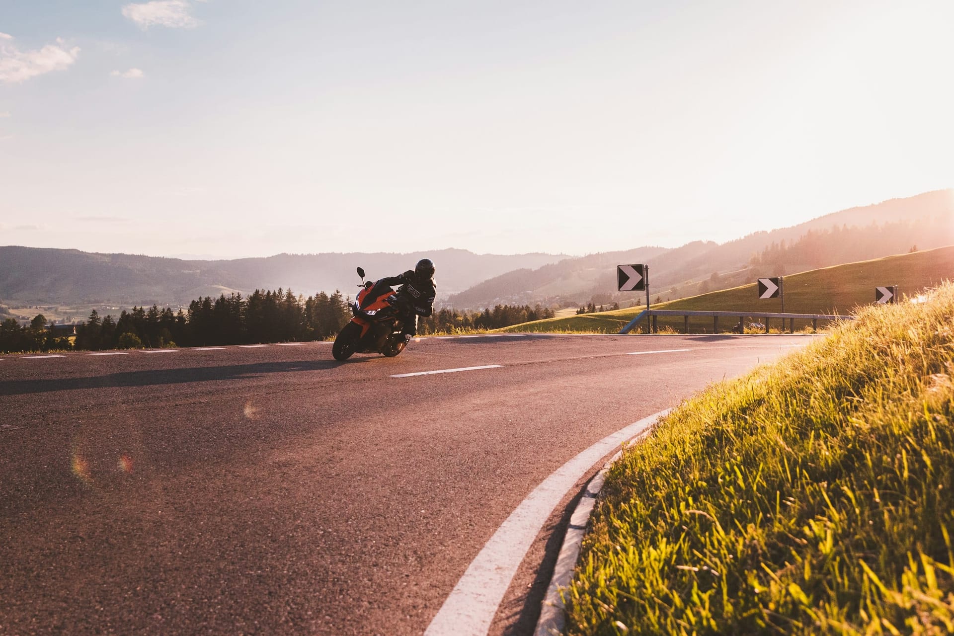 Motorrad in Schräglage auf einer blumengesäumten Landstraße im warmen Abendlicht